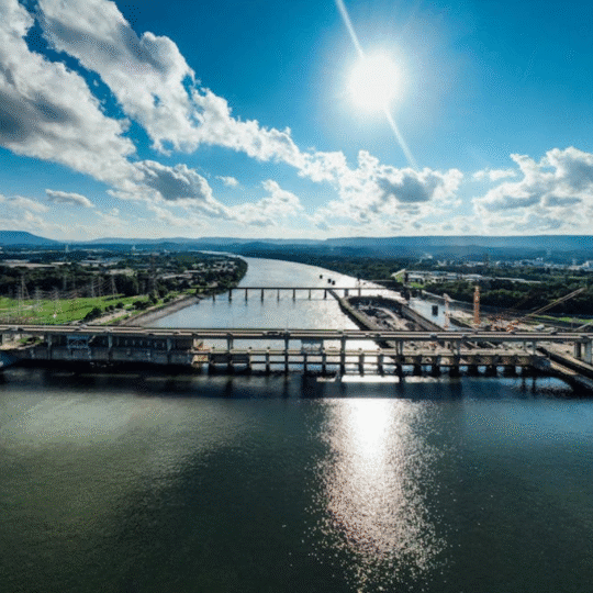 Sunlit view of the Tennessee River and industrial bridge in Chattanooga, capturing the essence of the Chattanooga landscape and local language