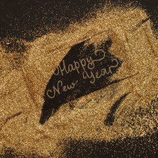 Gold glitter spelling out "Happy New Year," symbolizing new opportunities for a Chattanooga Business.