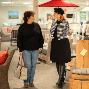 Two women talking inside a furniture showroom, representing customer service and relationship building for small business success.