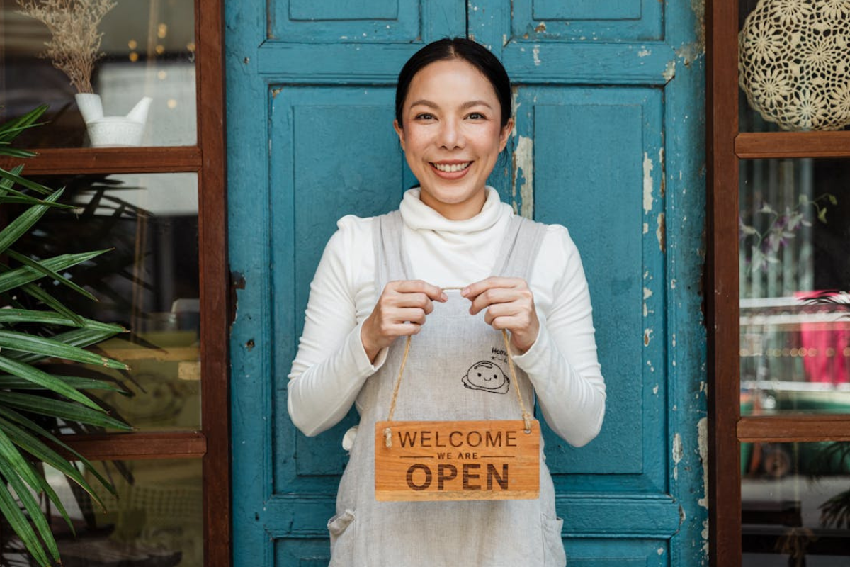 Small business owner holding an open sign, symbolizing brand authenticity and a welcoming local presence.