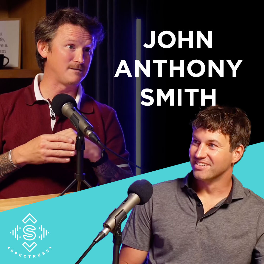 Podcast thumbnail for a Spectruss Speakeasy episode featuring John Anthony Smith, showing two guests speaking into microphones during a studio conversation.