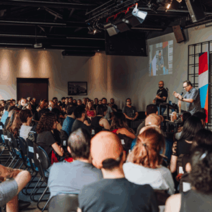 Large group of people attending a speaker event, demonstrating the power of in-person business networking and local engagement.