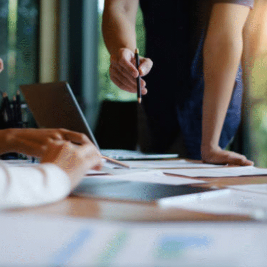 Business team reviewing marketing strategy with a Social Media Manager analyzing performance reports on laptop and documents.