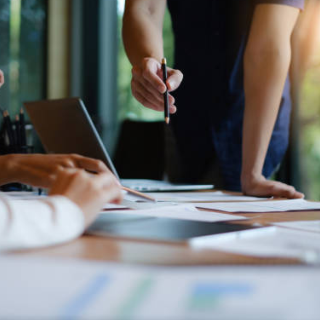 Business team reviewing marketing strategy with a Social Media Manager analyzing performance reports on laptop and documents.