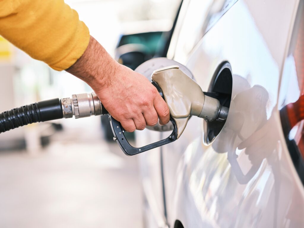 Driver fueling a silver car at the pump as rising gas prices change how local customers spend