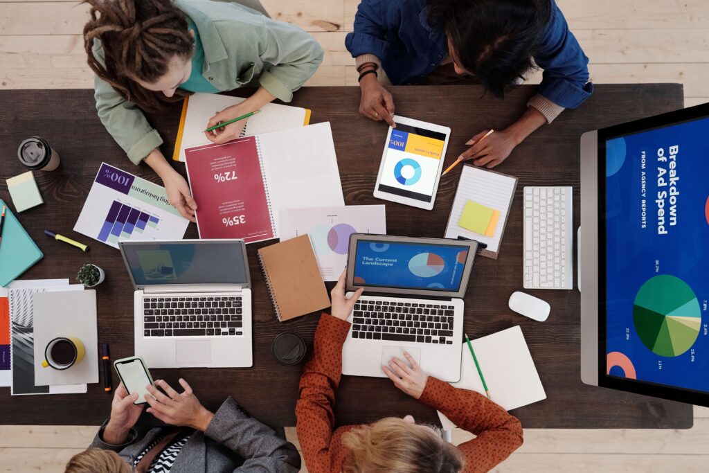 Overhead view of a team reviewing ad spend charts and budgets while weighing the cost of a Fractional CMO vs. Full-Time CMO