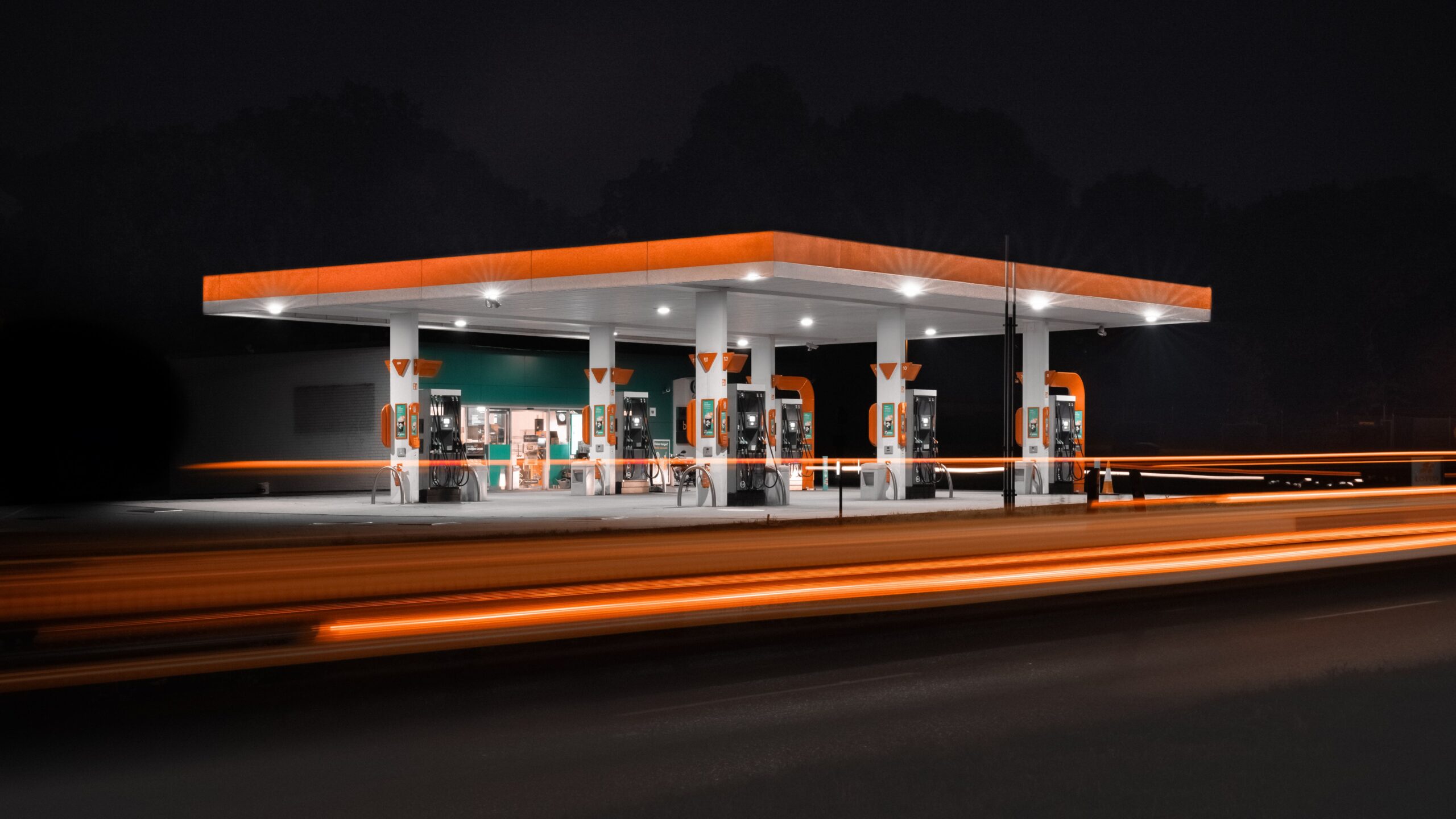 Gas station at night with light trails from passing traffic as rising gas prices affect where drivers spend